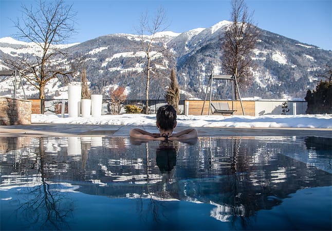 Vanuit het verwarmde buitenzwembad van Hotel Held kun je heerlijk genieten van het uitzicht op de besneeuwde bergen van het Zillertal. © Sport- & Wellnesshotel Held